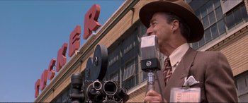 Movie still from “Tucker: The Man and His Dream” (1988), directed by Francis Ford Coppola – An older man in a suit and hat talking into a microphone; Medium shot, Low angle
