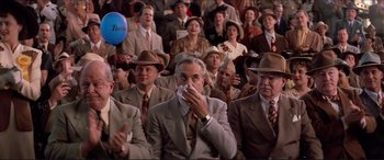 Movie still from “Tucker: The Man and His Dream” (1988), directed by Francis Ford Coppola – A group of people in suits and hats sitting in a room; Medium shot, Low angle