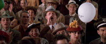 Movie still from “Tucker: The Man and His Dream” (1988), directed by Francis Ford Coppola – A man in a crowd of people wearing hats and smoking; Medium shot, Low angle