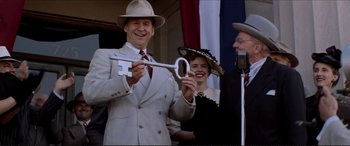 Movie still from “Tucker: The Man and His Dream” (1988), directed by Francis Ford Coppola – A man in a suit and hat holding up a key; Medium shot, High angle