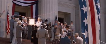 Movie still from “Tucker: The Man and His Dream” (1988), directed by Francis Ford Coppola – A group of people standing in front of a white building; Extreme Wide shot, Low angle