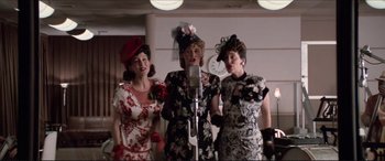 Movie still from “Tucker: The Man and His Dream” (1988), directed by Francis Ford Coppola – A group of three women standing next to each other in front of microphones; Medium shot, Low angle