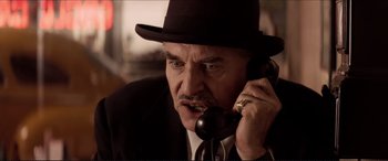 Movie still from “Tucker: The Man and His Dream” (1988), directed by Francis Ford Coppola – An older man wearing a black hat talking on a phone; Close Up shot, Low angle