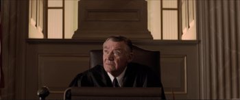 Movie still from “Tucker: The Man and His Dream” (1988), directed by Francis Ford Coppola – An older man in a judge's robe sitting in a chair; Medium shot, High angle
