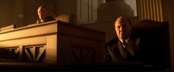 Movie still from “Tucker: The Man and His Dream” (1988), directed by Francis Ford Coppola – A man sitting in front of a podium in a court room; Medium shot, Low angle