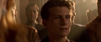 Movie still from “Tucker: The Man and His Dream” (1988), directed by Francis Ford Coppola – A young man in a brown jacket looking at the camera; Close Up shot, Over the shoulder angle