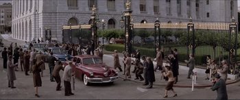 Movie still from “Tucker: The Man and His Dream” (1988), directed by Francis Ford Coppola – A group of people walking down a street next to a car; Extreme Wide shot, High angle