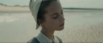 Movie still from “Tulip Fever” (2017), directed by Justin Chadwick – A young woman with her eyes closed on the beach; Close Up shot, Over the shoulder angle