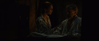 Movie still from “Tulip Fever” (2017), directed by Justin Chadwick – A woman sitting on a bed next to an older man; Medium shot, Over the shoulder angle