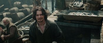 Movie still from “Tulip Fever” (2017), directed by Justin Chadwick – A man with long hair and a beard is smiling; Medium shot, High angle