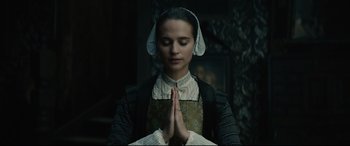 Movie still from “Tulip Fever” (2017), directed by Justin Chadwick – A young woman in an elizabethan era dress praying; Close Up shot, Low angle