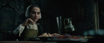 Movie still from “Tulip Fever” (2017), directed by Justin Chadwick – A woman sitting at a table with a glass of wine; Close Up shot, Over the shoulder angle