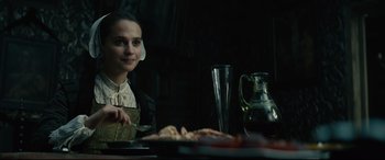 Movie still from “Tulip Fever” (2017), directed by Justin Chadwick – A woman sitting at a table with a plate of food in front of her; Close Up shot, Over the shoulder angle