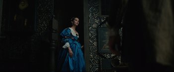 Movie still from “Tulip Fever” (2017), directed by Justin Chadwick – A woman in a blue dress standing in front of a painting; Medium shot, Low angle