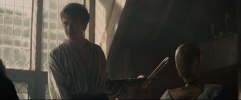 Movie still from “Tulip Fever” (2017), directed by Justin Chadwick – A young man holding a tray in front of a window; Medium shot, Over the shoulder angle
