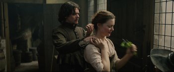 Movie still from “Tulip Fever” (2017), directed by Justin Chadwick – A man and a woman in medieval garb are fixing each other's hair; Medium shot, Over the shoulder angle