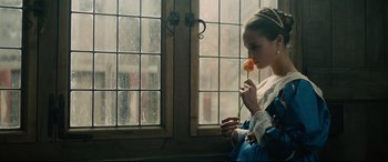 Movie still from “Tulip Fever” (2017), directed by Justin Chadwick – A young woman holding a flower in front of a window; Close Up shot, Over the shoulder angle