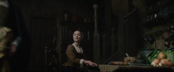 Movie still from “Tulip Fever” (2017), directed by Justin Chadwick – A woman sitting in front of a table in a dark room; Medium shot, Low angle
