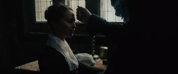 Movie still from “Tulip Fever” (2017), directed by Justin Chadwick – A woman in a black dress is getting her hair cut by a man; Close Up shot, Over the shoulder angle