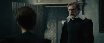 Movie still from “Tulip Fever” (2017), directed by Justin Chadwick – A man with a beard standing in front of a mirror; Medium shot, Over the shoulder angle