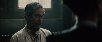 Movie still from “Tulip Fever” (2017), directed by Justin Chadwick – A man with a goatee is looking at another man; Close Up shot, Over the shoulder angle