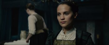 Movie still from “Tulip Fever” (2017), directed by Justin Chadwick – A young woman in a green dress looking at the camera; Close Up shot, Over the shoulder angle