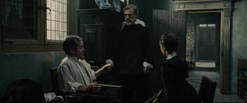 Movie still from “Tulip Fever” (2017), directed by Justin Chadwick – Two men and a woman are in a room; Medium shot, Over the shoulder angle