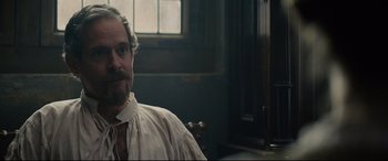 Movie still from “Tulip Fever” (2017), directed by Justin Chadwick – A man with a beard is sitting in front of a window; Close Up shot, Over the shoulder angle