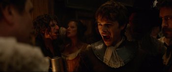 Movie still from “Tulip Fever” (2017), directed by Justin Chadwick – A group of people in medieval garb singing in a room; Medium shot, Low angle