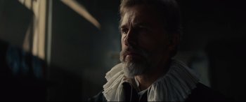 Movie still from “Tulip Fever” (2017), directed by Justin Chadwick – A man with a long beard wearing a white shirt and a neck tie; Close Up shot, Low angle