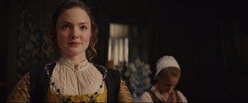 Movie still from “Tulip Fever” (2017), directed by Justin Chadwick – A woman in a yellow and black dress standing next to another woman in a white dress; Close Up shot, Over the shoulder angle