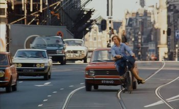Movie still from “Turkish Delight” (1973), directed by Paul Verhoeven – Two women riding a bicycle down a street with cars; Wide shot, Low angle
