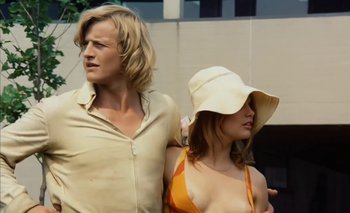 Movie still from “Turkish Delight” (1973), directed by Paul Verhoeven – A man and a woman standing next to each other in front of a building; Medium shot, Low angle