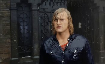 Movie still from “Turkish Delight” (1973), directed by Paul Verhoeven – A man with long blonde hair wearing a black jacket; Medium shot, Low angle