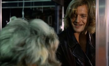 Movie still from “Turkish Delight” (1973), directed by Paul Verhoeven – A man in a leather jacket is smiling at a dog; Close Up shot, Over the shoulder angle