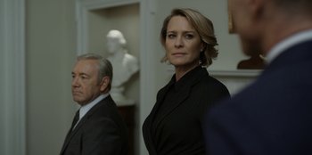 Movie still from “House of Cards” (2013), created by Beau Willimon – A woman standing next to a man wearing a suit; Close Up shot, Over the shoulder angle