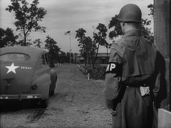 Movie still from “Twelve O'Clock High” (1949), directed by Henry King – An old photo of a man in a military uniform looking at an old car; Wide shot, Over the shoulder angle