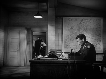 Movie still from “Twelve O'Clock High” (1949), directed by Henry King – A man sitting at a desk in front of a map; Wide shot, High angle