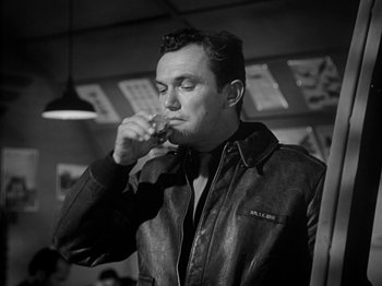 Movie still from “Twelve O'Clock High” (1949), directed by Henry King – A black and white photo of a man smoking a cigarette; Medium shot, Low angle