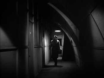 Movie still from “Twelve O'Clock High” (1949), directed by Henry King – A man standing in a dark hallway with a light on; Wide shot, Low angle