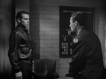 Movie still from “Twelve O'Clock High” (1949), directed by Henry King – Two men are standing next to each other in front of a brick wall; Medium shot, Over the shoulder angle