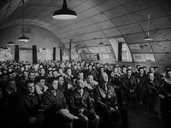 Movie still from “Twelve O'Clock High” (1949), directed by Henry King – A group of men sitting in rows in a room; Wide shot, High angle