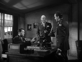 Movie still from “Twelve O'Clock High” (1949), directed by Henry King – Three military men are shaking hands over a desk; Medium shot, Low angle