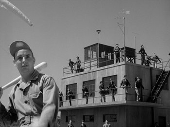 Movie still from “Twelve O'Clock High” (1949), directed by Henry King – A group of men standing on top of a tall building; Wide shot, Low angle