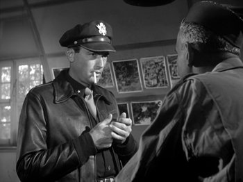 Movie still from “Twelve O'Clock High” (1949), directed by Henry King – A man in a leather jacket talking to another man in a hat; Medium shot, Over the shoulder angle