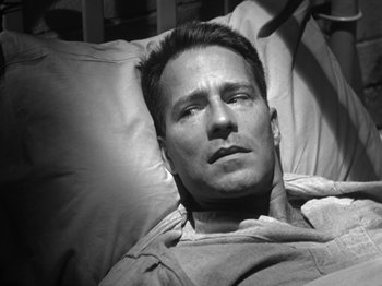 Movie still from “Twelve O'Clock High” (1949), directed by Henry King – A black and white photo of a man laying in bed; Close Up shot, High angle