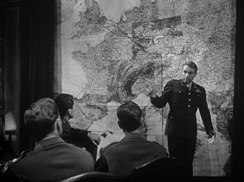 Movie still from “Twelve O'Clock High” (1949), directed by Henry King – A man in a military uniform standing in front of a map; Medium shot, Over the shoulder angle
