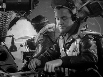 Movie still from “Twelve O'Clock High” (1949), directed by Henry King – A man in an airplane cockpit working on a computer; Medium shot, Low angle