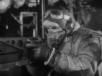 Movie still from “Twelve O'Clock High” (1949), directed by Henry King – A man wearing a helmet and goggles working on a machine gun; Medium shot, Low angle