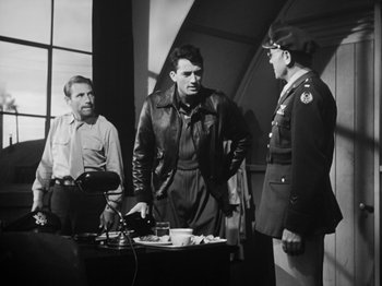 Movie still from “Twelve O'Clock High” (1949), directed by Henry King – A man in a leather jacket standing next to two other men; Medium shot, Over the shoulder angle
